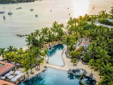 Aerial view of a luxury beachfront resort in Mauritius with a pool and yachts in a turquoise lagoon