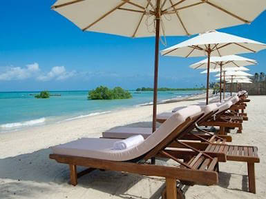 Relaxing white sand beach in Zanzibar with wooden loungers and sun umbrellas by turquoise waters