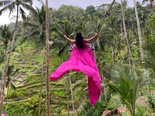 Woman in pink dress on famous Bali swing overlooking Ubud rice terraces