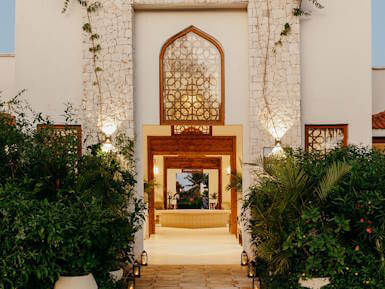 Entrance architecture at LUX* Marijani resort in Zanzibar surrounded by tropical greenery.