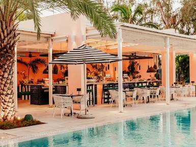 Poolside restaurant and bar area at a luxury beach resort in Mauritius with palm trees and outdoor seating.